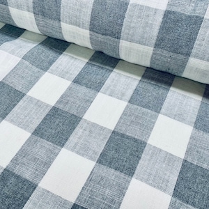 Puede incluir: Primer plano de una tela de vichy blanca y gris con textura tejida. La tela tiene un patrón a cuadros con cuadrados grandes.