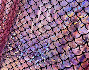 May include: Close-up of a fabric with a mermaid scale pattern. The scales are a mix of pink, purple, and iridescent colors, outlined in black. The fabric has a shimmering, holographic effect, creating a textured and visually dynamic surface.
