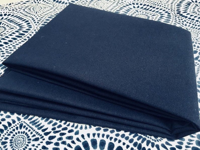 May include: A folded piece of dark blue fabric. The fabric has a smooth texture and is folded neatly.
