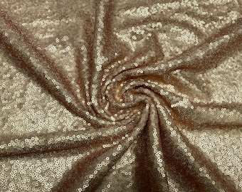 May include: A close-up of a gold sequined fabric. The sequins are small and tightly packed, creating a shimmering effect.