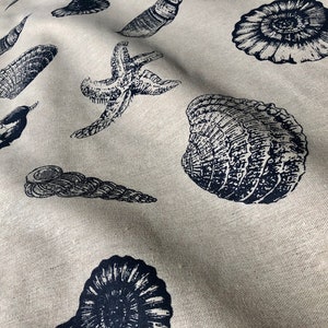 May include: A beige fabric with a repeating pattern of black and white sea life illustrations. The pattern includes starfish, seashells, and seahorses.