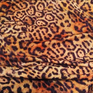 May include: Close-up of a fabric with a brown and black leopard print pattern. The fabric is folded and has a soft, textured surface.