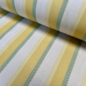 Peut inclure: Gros plan sur un rouleau de tissu avec un motif rayé répétitif. Le motif comprend des rayures verticales jaunes, blanches et vertes. Les rayures vertes ont un motif en chevrons. Le tissu semble être du coton ou une matière similaire.