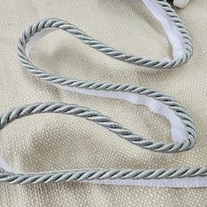 May include: Silver braided trim with a white backing. The trim is a decorative rope-like material.