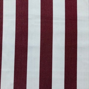 May include: Close-up of a fabric with vertical stripes. Alternating wide stripes of white and burgundy create a bold pattern. The fabric appears to be smooth and likely suitable for various sewing projects.