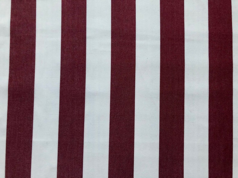 May include: Close-up of a fabric with vertical stripes. Alternating wide stripes of white and burgundy create a bold pattern. The fabric appears to be smooth and likely suitable for various sewing projects.