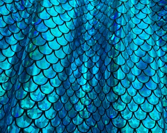 May include: Close-up of iridescent blue fabric with a mermaid scale pattern. The scales are outlined in black and have a shiny, holographic finish.
