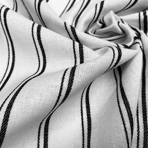 May include: White fabric with black stripes. The fabric is wrinkled and folded.