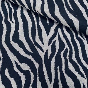 Pode incluir: Tecido de estampa de zebra preto e branco com um visual de linho texturizado. O tecido está dobrado ao meio, mostrando o padrão em ambos os lados.