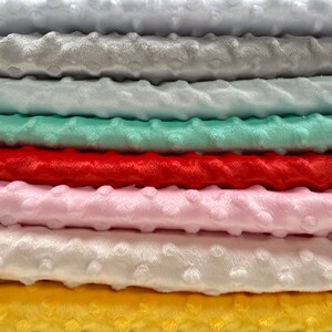 May include: A stack of eight different colors of soft, plush fabric. The colors are white, silver grey, sky blue, mint green, carrot red, baby pink, blush pink, and yellow.
