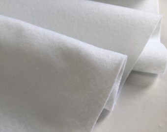 May include: Close-up of white felt fabric, showing the texture and folds of the material. The fabric appears soft and slightly translucent, with a clean, bright appearance. Ideal for crafting and DIY projects.