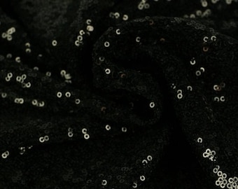 May include: Black fabric with silver sequins. The fabric is bunched up and the sequins are scattered randomly.