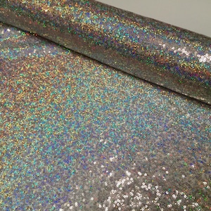 May include: A roll of iridescent silver fabric with a sparkly, sequin-like texture.