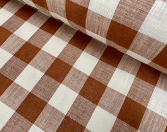Pode incluir: Tecido gingham marrom e branco com textura tecida. O tecido está dobrado ao meio, mostrando o padrão em ambos os lados.