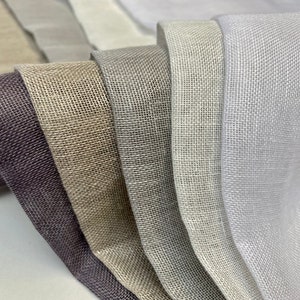 Puede incluir: Primer plano de seis muestras de tela en diferentes tonos de gris, beige y blanco. La tela tiene una textura tejida y un brillo sutil.