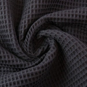 May include: Close-up of a dark gray waffle weave fabric. The fabric is soft and textured, with a subtle sheen.