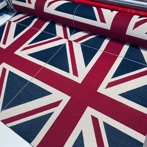 May include: A close-up of a fabric with a repeating pattern of the Union Jack flag. The fabric is red, white, and blue.