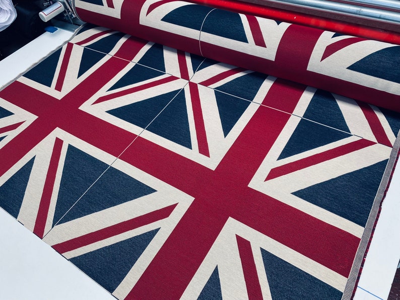 May include: A close-up of a fabric with a repeating pattern of the Union Jack flag. The fabric is red, white, and blue.