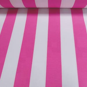 May include: Close-up of a roll of fabric with vertical stripes. Alternating stripes of bright pink and white create a bold pattern. The fabric appears to be a medium weight material, suitable for various sewing projects.
