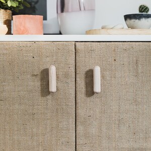 May include: Two cabinet doors with a natural burlap fabric covering. Each door has a simple, light wood knob.