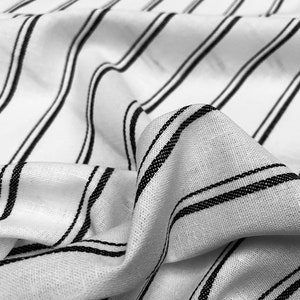 May include: White fabric with black stripes. The fabric is wrinkled and has a soft texture.