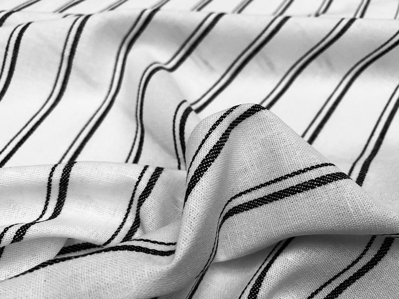 May include: White fabric with black stripes. The fabric is wrinkled and has a soft texture.