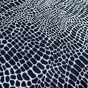 May include: Black and white fabric with a textured snake skin pattern.