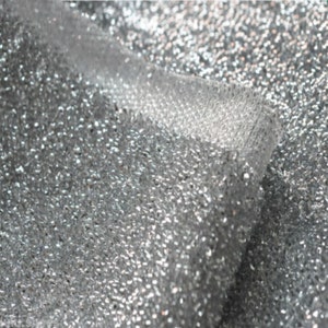 May include: Silver glitter fabric with a textured, sparkly surface.