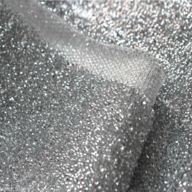 May include: Silver glitter fabric with a textured, sparkly surface.