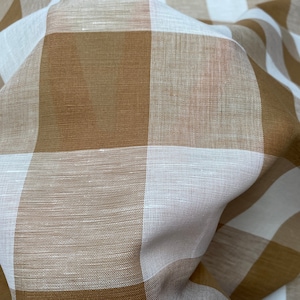 May include: A white and brown gingham fabric with a woven texture. The fabric is folded and draped, showing the pattern and texture.