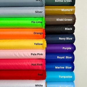 Puede incluir: Una exhibición de rollos de tela en varios colores, incluyendo gris, plata, verde lima, naranja, amarillo, rosa pálido, rosa intenso, rojo y blanco. Colores adicionales son verde botella, mostaza, caqui, negro, azul marino, morado, azul real, azul marino, turquesa y azul pálido.
