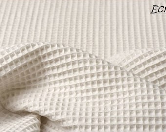 May include: An ecru colored fabric featuring a distinct waffle weave texture. The material is draped to show the depth of the grid pattern. The word Ecru is printed in the upper right corner of the image in a simple black font.
