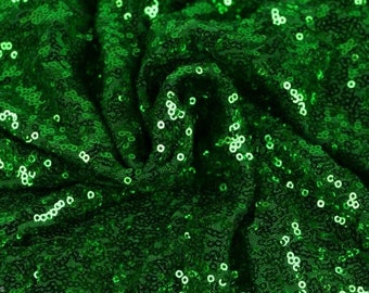May include: Green sequin fabric with a shiny, iridescent finish. The fabric is tightly woven and has a smooth texture.