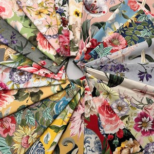 Könnte beinhalten: Eine Sammlung von Stoffmustern mit Blumenmustern, die kreisförmig angeordnet sind. Die Stoffe weisen eine Vielzahl farbenfroher Blumenmuster auf, darunter Rosen, Tulpen und andere Blüten, in Rosa-, Rot-, Gelb- und Blautönen. Die Stoffe sind wahrscheinlich aus Baumwolle oder Leinen.