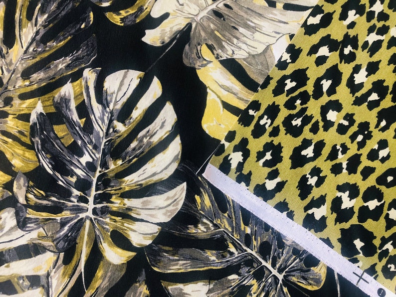 May include: Two fabric swatches, one with a black and white tropical leaf pattern and the other with a black and yellow leopard print.