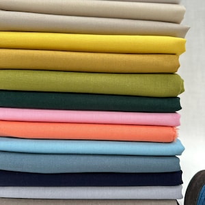 May include: A stack of 14 different coloured fabric swatches. The colours are white, beige, yellow, mustard, green, dark green, pink, orange, light blue, blue, grey, brown, and black.