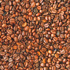 Könnte beinhalten: Ein Nahaufnahmebild einer großen Menge gerösteter Kaffeebohnen. Die Bohnen sind von einer satten braunen Farbe und haben einen leicht öligen Glanz.