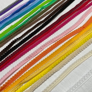 Puede incluir: Surtido de cintas de adorno con pompones de varios colores, incluyendo rojo, naranja, amarillo, verde, azul, morado y blanco.