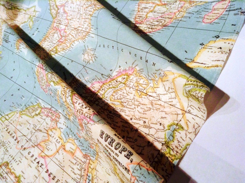 May include: A vintage style world map printed on fabric. The map is folded in half and shows a portion of North America, Europe, and Africa. The map is printed in shades of blue, green, brown, and yellow.