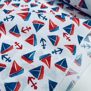 May include: White fabric with a repeating pattern of red and blue sailboats and anchors.