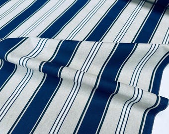 May include: Close-up of a fabric with a repeating striped pattern. The design features alternating wide navy blue stripes, thin white stripes, and a neutral beige background. The fabric is folded, showing the texture and drape.