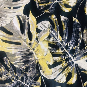 May include: A black fabric with a tropical leaf pattern in shades of yellow, gray, and white.