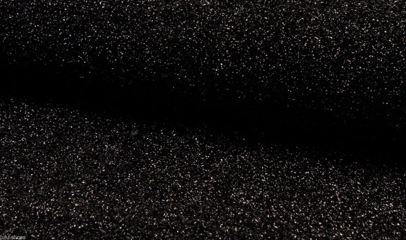 May include: Black fabric with a sparkly, glittery texture. The fabric is folded in half, creating a crease down the center.