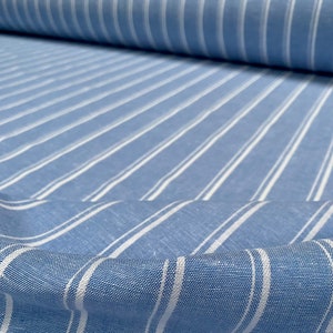 Pu&ograve; includere: Tessuto a righe blu e bianche con una trama di lino. Il tessuto &egrave; piegato e mostra le righe che corrono verticalmente.