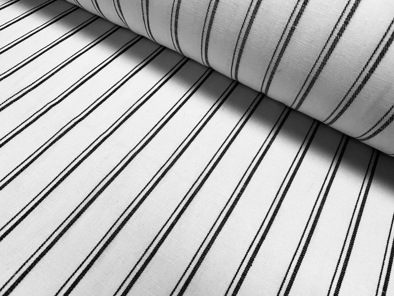 May include: White fabric with thin black stripes. The fabric is folded in half, showing the stripes running diagonally.
