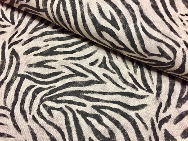 Peut inclure: Gros plan sur un tissu blanc avec un motif z&egrave;bre noir. Le tissu est pli&eacute;, montrant le motif des deux c&ocirc;t&eacute;s.