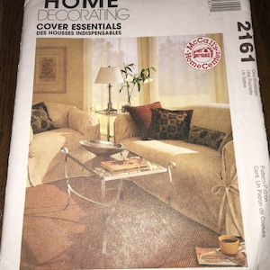 May include: McCall's Home Decorating Cover Essentials sewing pattern featuring a photograph of a living room with a sofa, two side tables, a lamp, and a coffee table. The pattern number is 2161.