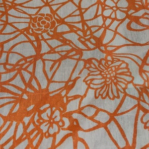 Puede incluir: Patrón floral naranja sobre un fondo de tela blanca. El patrón presenta un diseño repetitivo de flores y enredaderas.