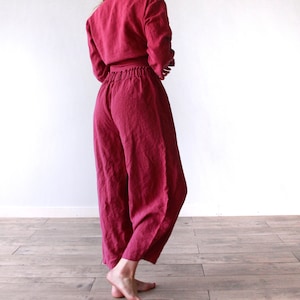 May include: A deep red linen jumpsuit with a wide leg and a cinched waist.