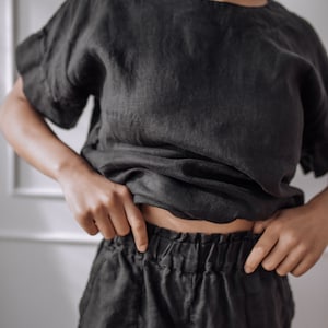 Peut inclure: Un haut en lin noir &agrave; la coupe ample et aux manches courtes, associ&eacute; &agrave; un pantalon en lin noir avec une taille &eacute;lastique.